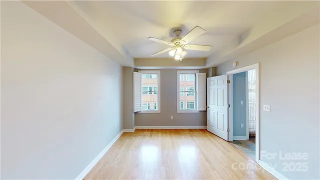 an empty room with windows and fan