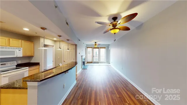 a kitchen with stainless steel appliances granite countertop a stove a refrigerator a sink and dishwasher with wooden floor