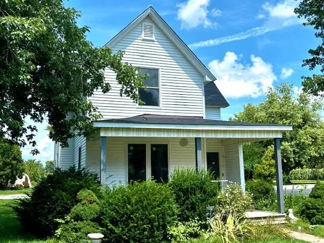 a view of a white house with a large window and potted plants