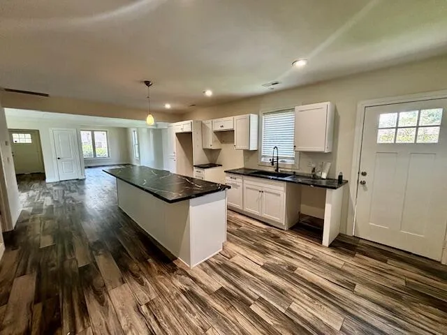 a large kitchen with granite countertop a stove top oven a sink and white cabinets