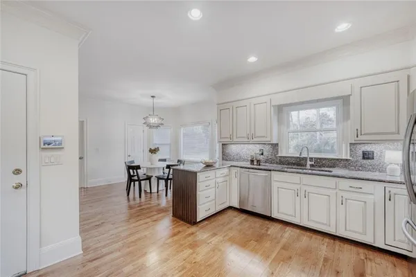 a kitchen with white cabinets sink and dining table chair