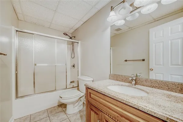 a bathroom with a granite countertop sink a toilet and shower
