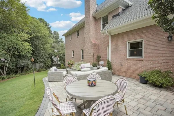 a view of a patio with couches table and chairs with plants and trees