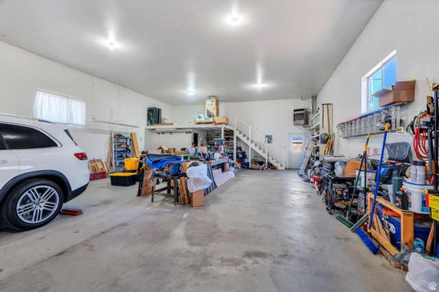 377 North 650 East, Unit 9 Orem, UT 84097 - Photo 8 of 9 Spacious garage with concrete flooring, multiple windows providing natural light, overhead lighting, a built-in mezzanine, and an internal staircase for access