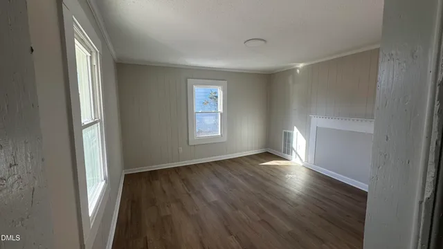 an empty room with wooden floor & windows