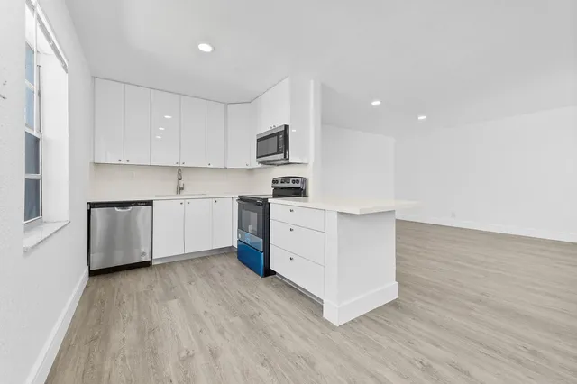 a kitchen with wooden floors and white stainless steel appliances