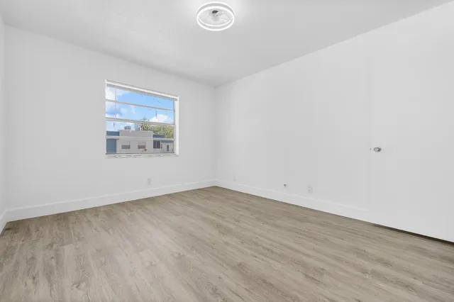 an empty room with wooden floor and window