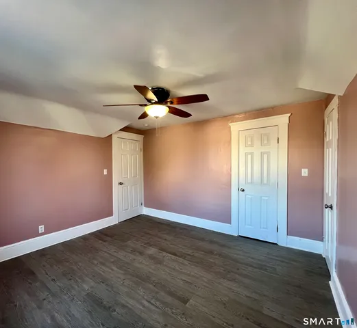 an empty room with wooden floor closet and windows