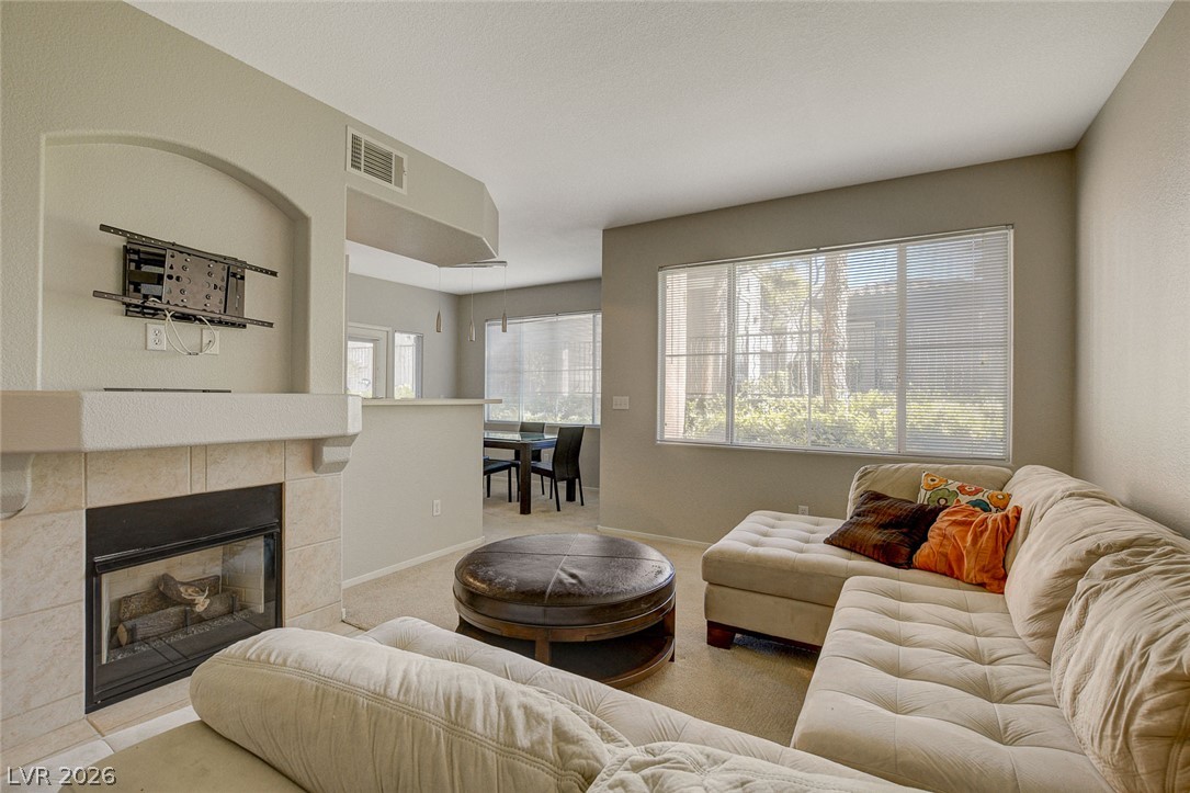 9050 West Warm Springs Road, Unit 1034 Las Vegas, NV 89148 - Photo 6 of 17 A welcoming living area with a cozy fireplace and adjacent dining space awaits.