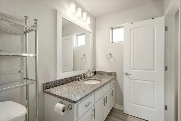 a bathroom with a granite countertop toilet a sink a mirror a shower curtain and a large mirror
