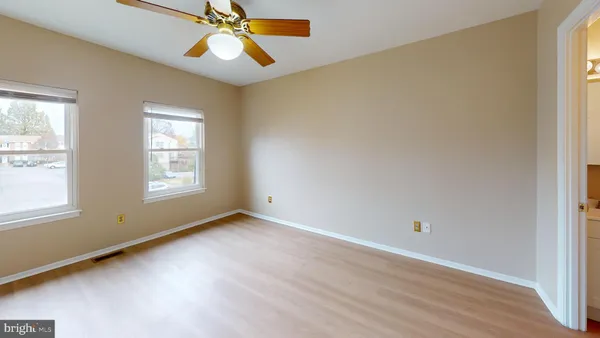 an empty room with windows and fan