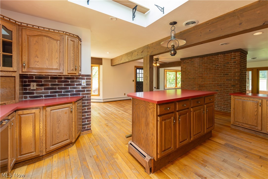 7969 Dines Road Novelty, OH 44072 - Photo 11 of 48 Kitchen featuring hardwood flooring, wood cabinetry, red countertops, large breakfast bar island, and exposed brick accents