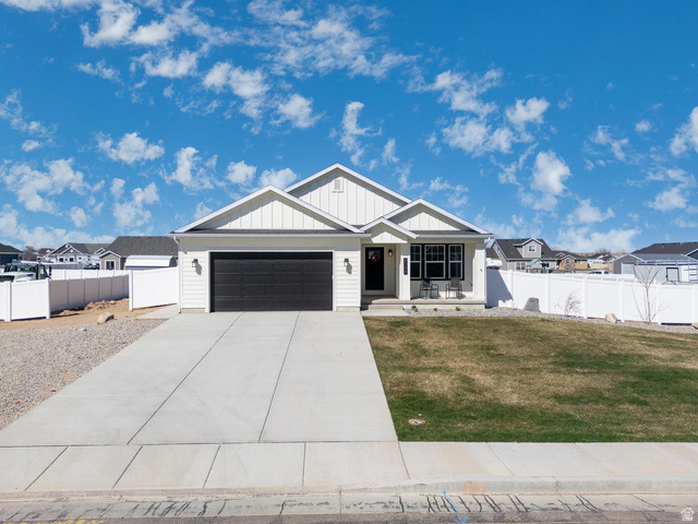 4349 Half Mile Road East Enoch, UT 84721 - Photo 2 of 36 View of front of home with a porch, an attached garage, driveway, board and batten siding, and a residential view