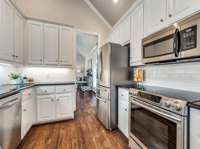 a kitchen with cabinets stainless steel appliances and wooden floor