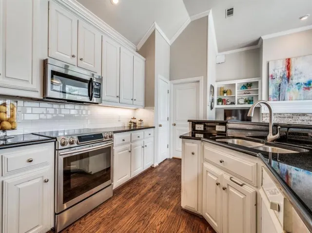 a kitchen with granite countertop wooden cabinets stainless steel appliances and a wooden floor