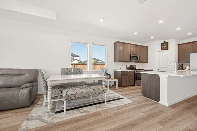 a living room with a couch and a dining table with wooden floor