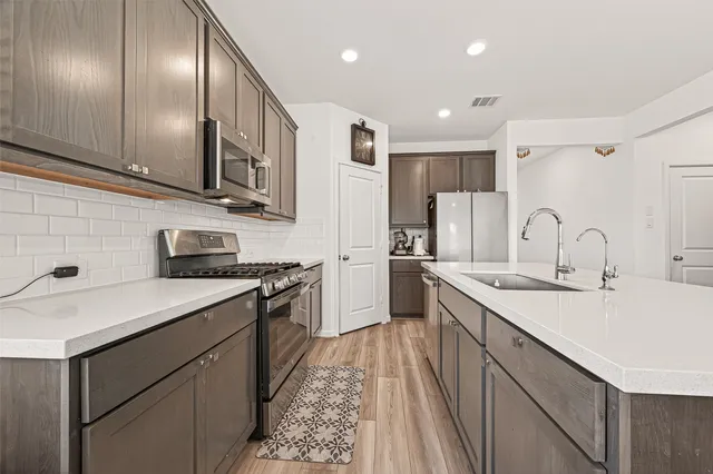 a kitchen with stainless steel appliances granite countertop cabinets a sink a stove a refrigerator and a oven