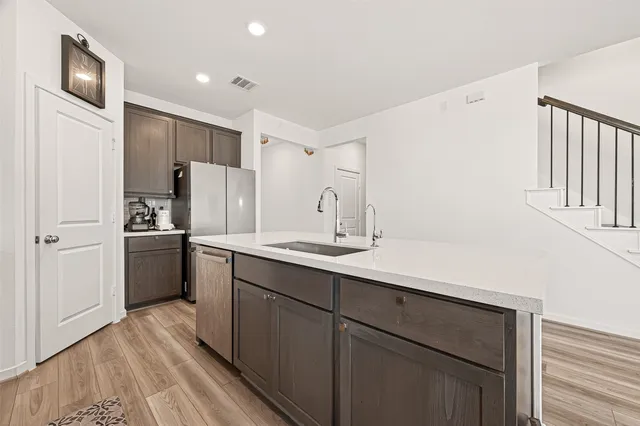 a kitchen with a sink stainless steel appliances a refrigerator and cabinets