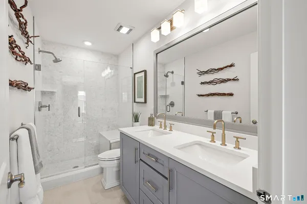a bathroom with a double vanity sink toilet mirror and shower