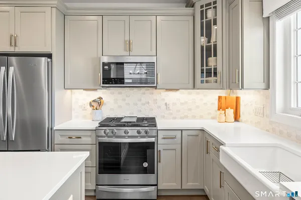 a kitchen with stainless steel appliances granite countertop a stove and a refrigerator with white cabinets