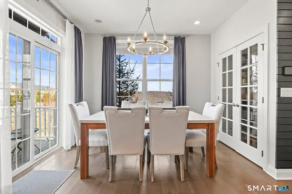 a dining room with wooden floor a chandelier a wooden table and chairs