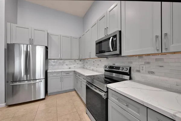 a kitchen with stainless steel appliances granite countertop white cabinets a microwave a stove and a refrigerator