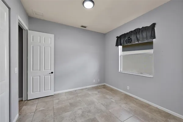 a view of an empty room with closet and a window