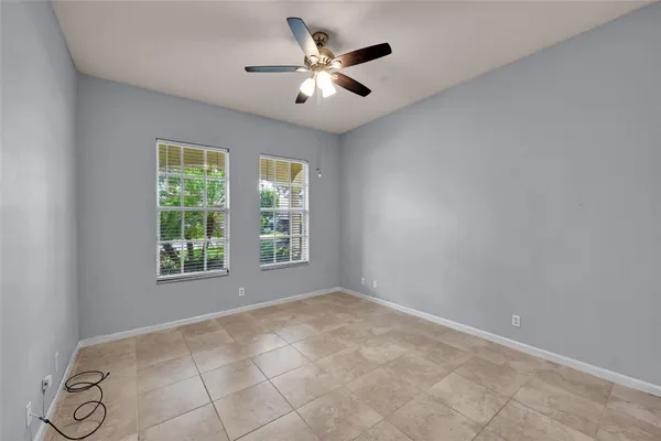 an empty room with windows and ceiling fan