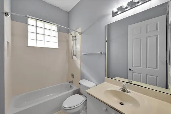 a bathroom with a bathtub shower sink vanity mirror and toilet