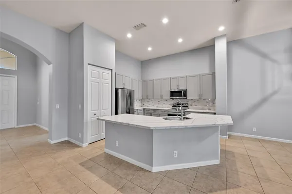 a view of kitchen with kitchen island stainless steel appliances a sink stove refrigerator and cabinets
