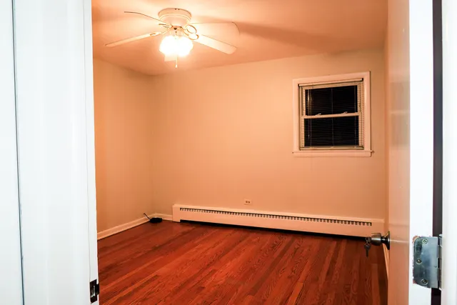 an empty room with wooden floor closet and windows