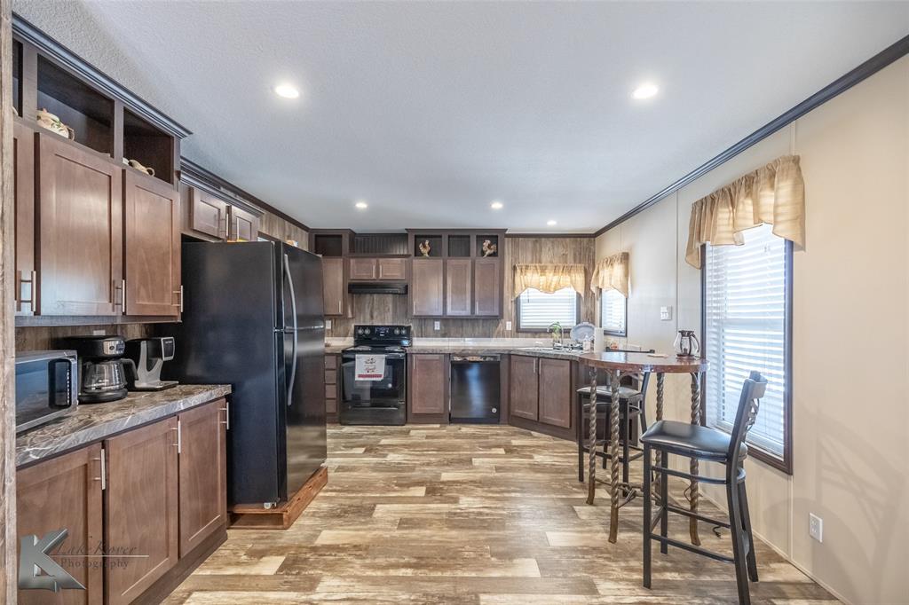 2302 County Road 360 Merkel, TX 79536 - Photo 9 of 39 a kitchen with stainless steel appliances granite countertop a refrigerator a stove a sink a dining table and chairs with wooden floor