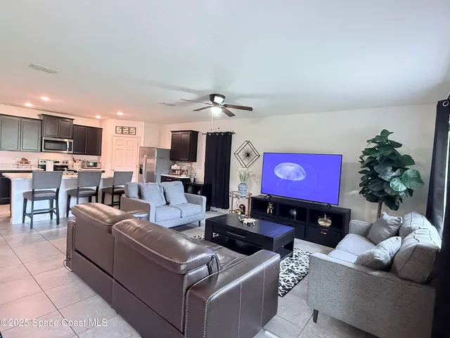 a living room with furniture a flat screen tv and kitchen view