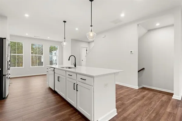 a large white kitchen with a large sink a oven and wooden floor