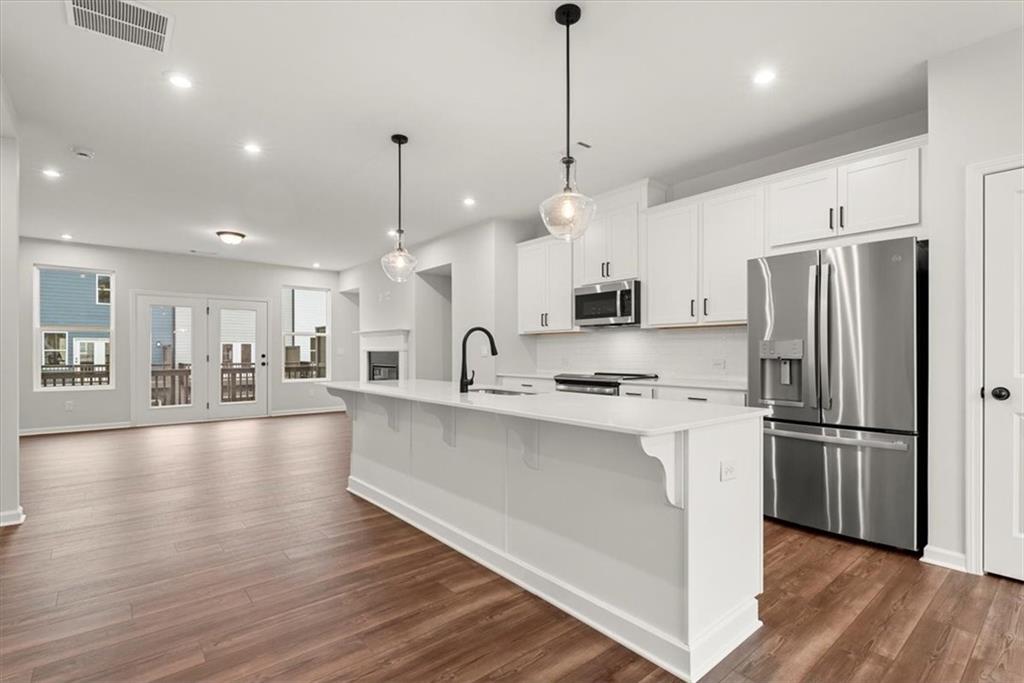 741 Payton Lane Acworth, GA 30102 - Photo 12 of 36 a large kitchen with stainless steel appliances a refrigerator a stove a sink dishwasher a oven and a dining table with wooden floor