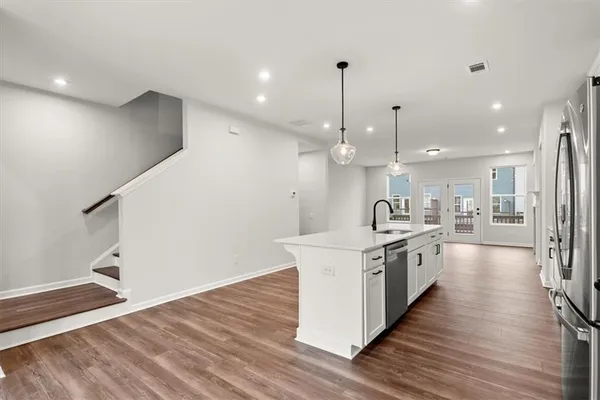 a large kitchen with stainless steel appliances kitchen island a large counter top and a wooden floors