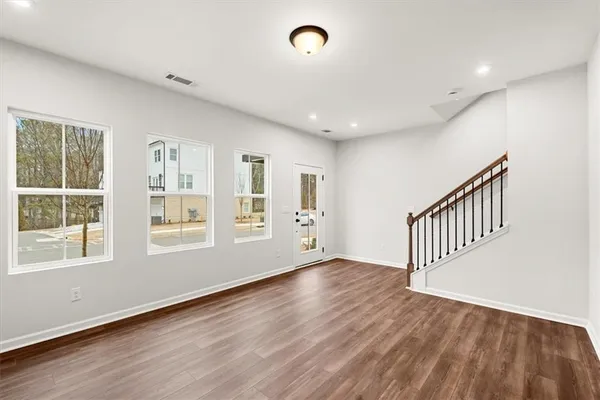 a view of an empty room with wooden floor and windows