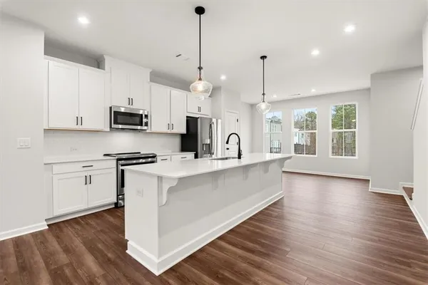 a large kitchen with granite countertop a stove a sink a center island and wooden floor