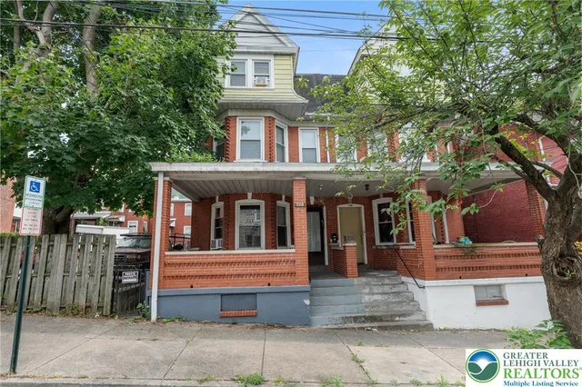 a front view of a house with a tree