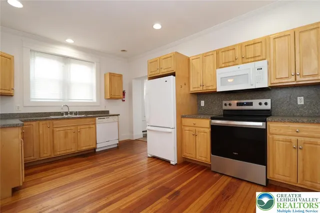 a kitchen with granite countertop wooden floors stainless steel appliances and window