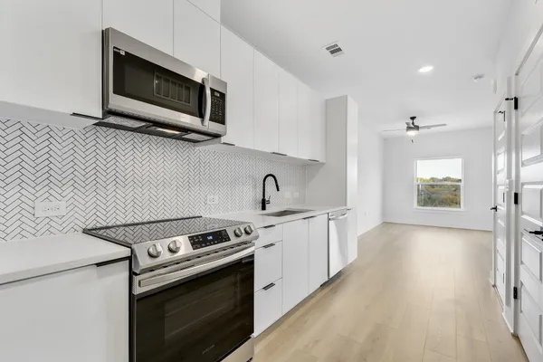 a kitchen with stainless steel appliances a stove microwave and sink