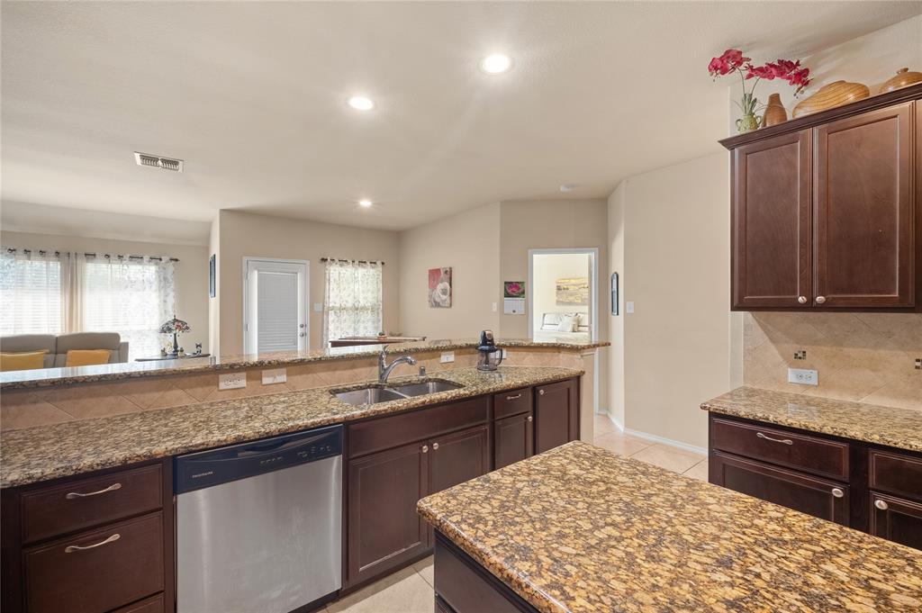 520 Rustic Oak Lane McKinney, TX 75072 - Photo 12 of 30 Kitchen featuring rich wood cabinetry, granite countertops, a stainless steel dishwasher, a double basin sink with a gooseneck faucet, and recessed lighting