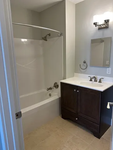 a bathroom with a tub sink vanity granite and a mirror