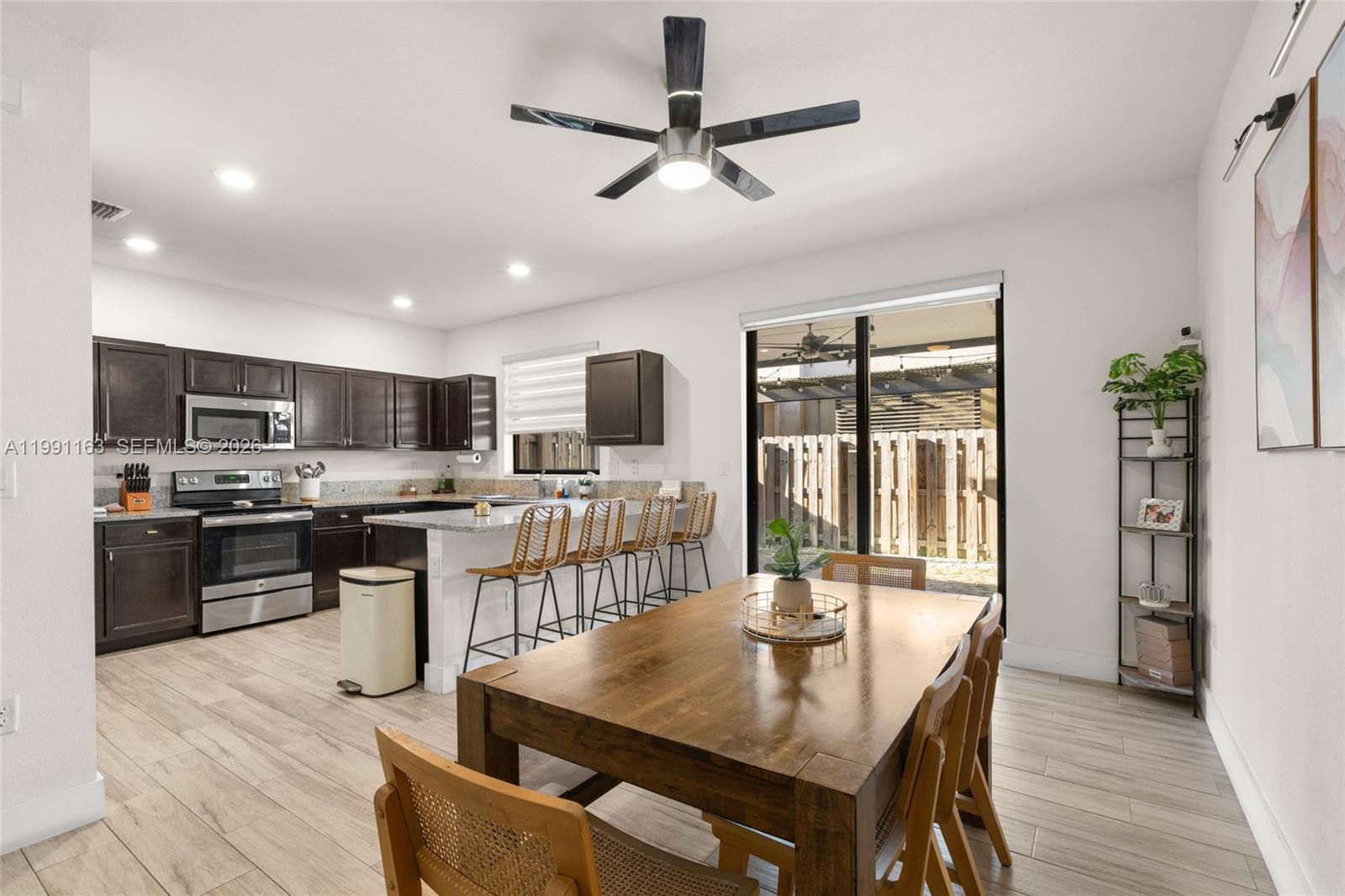 11429 Southwest 253rd Street Homestead, FL 33032 - Photo 9 of 30 a kitchen with stainless steel appliances kitchen island granite countertop a table chairs and a refrigerator