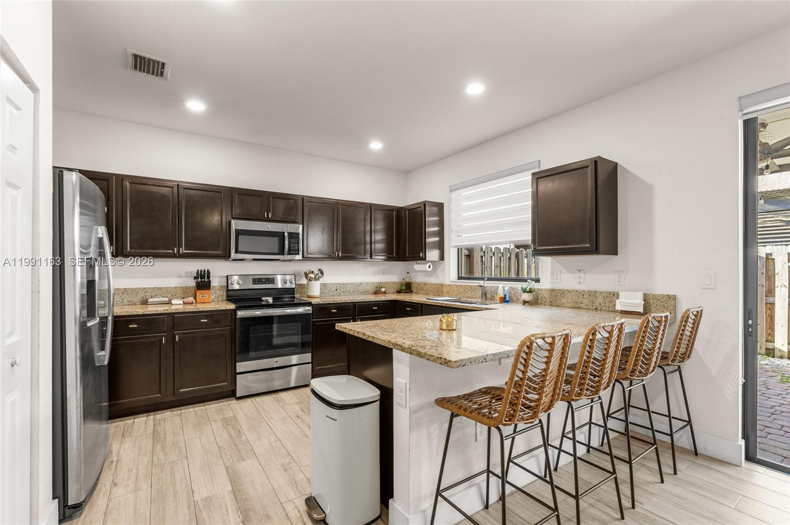 11429 Southwest 253rd Street Homestead, FL 33032 - Photo 10 of 30 a kitchen with stainless steel appliances granite countertop a stove top oven a sink dishwasher a dining table and chairs