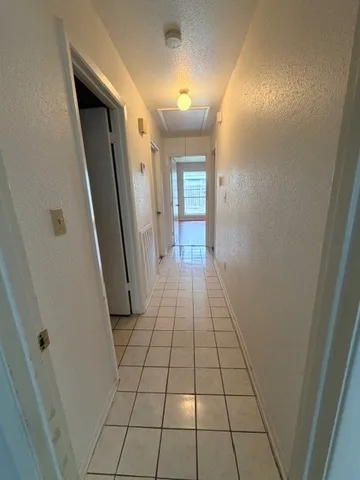 a view of a hallway with wooden floor and a bathroom