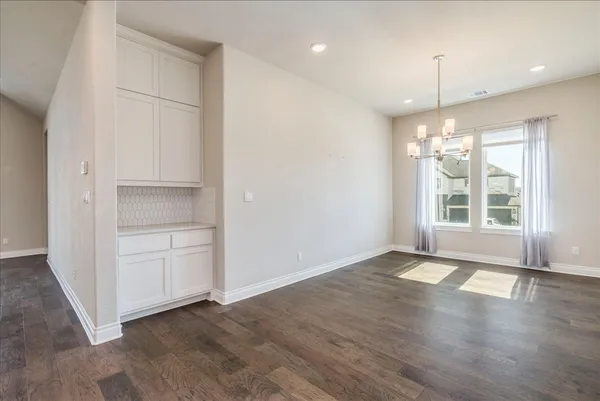 an empty room with wooden floor cabinet and windows