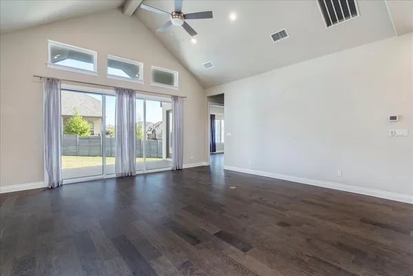a view of an empty room with a window and wooden floor