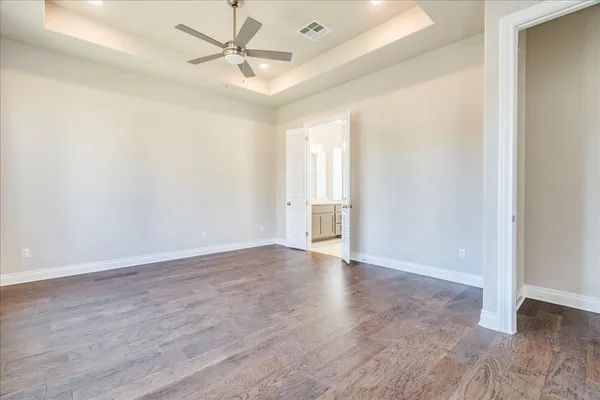 an empty room with wooden floor and ceiling fan