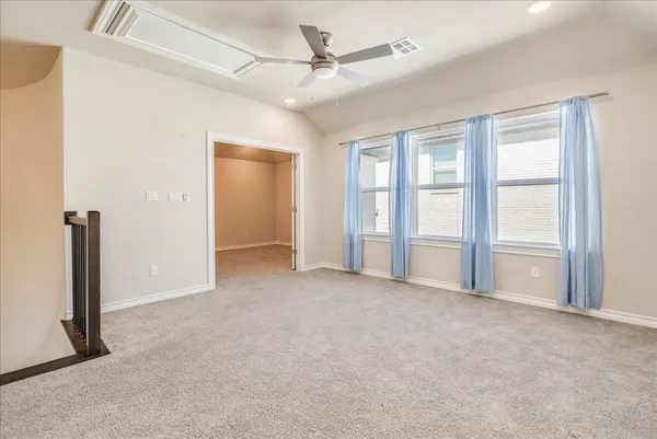 an empty room with windows and ceiling fan